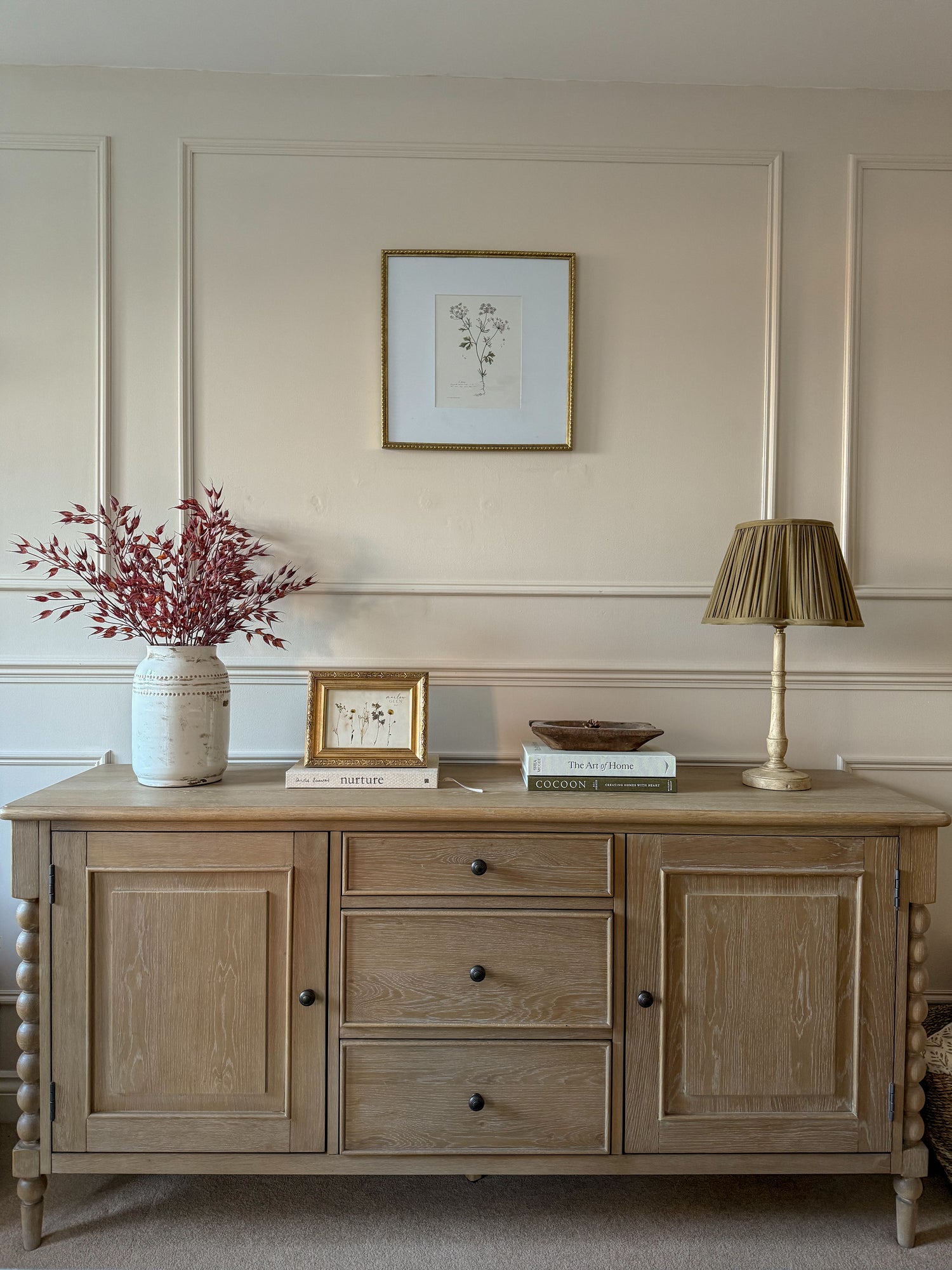 Wooden sideboard with decorative items against a wall with paneling