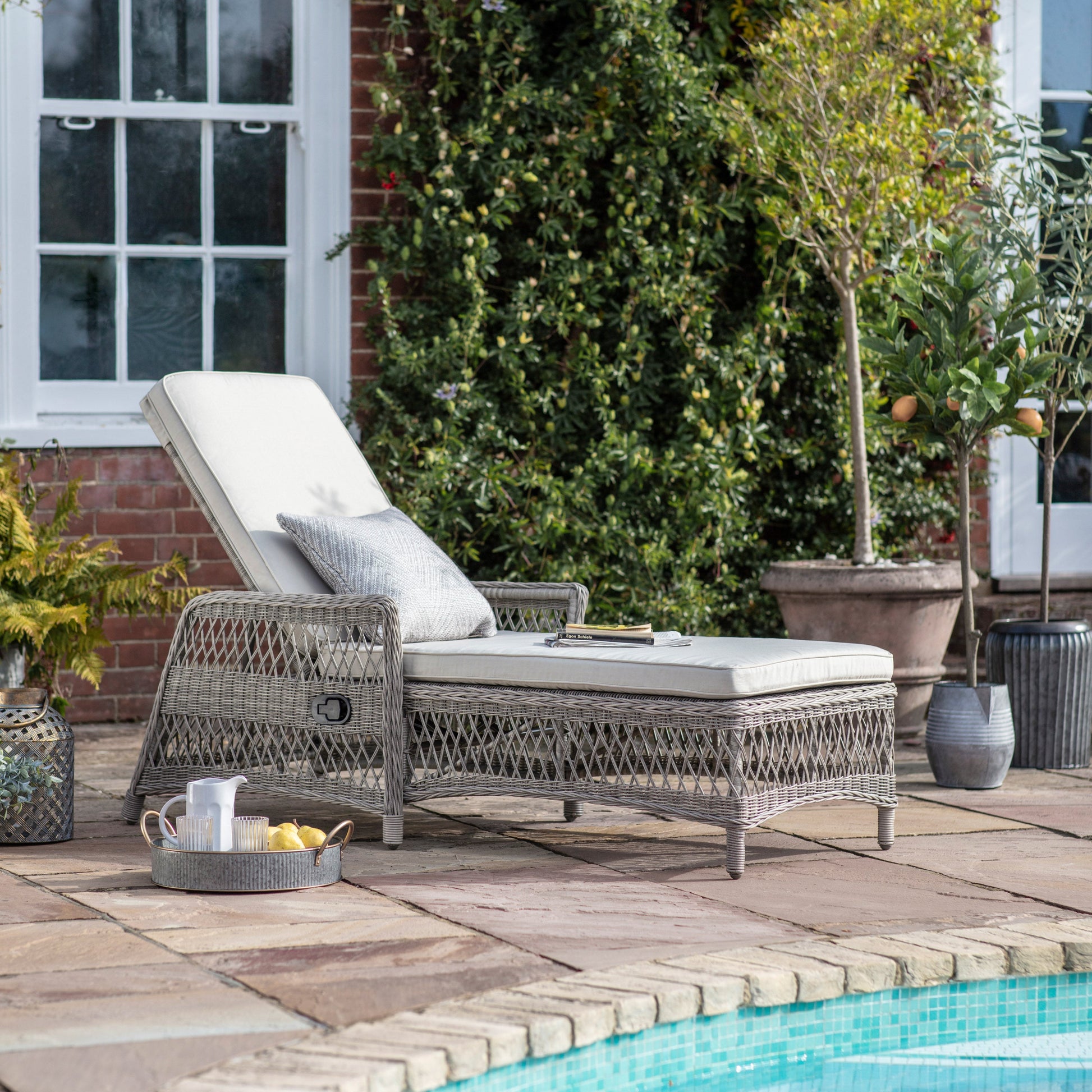 Outdoor lounge chair with cushions on a patio by a pool