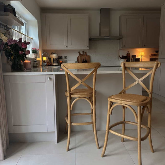Kitchen with light gray cabinets, white countertops, and wooden bar stools.