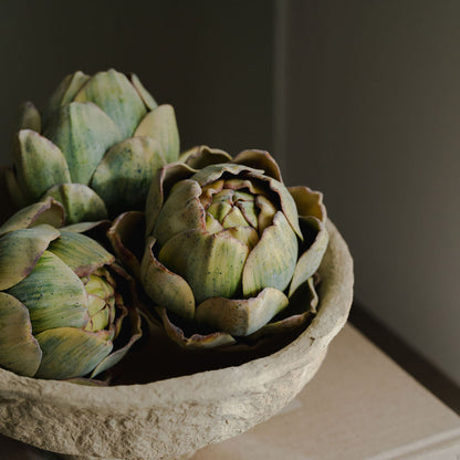 Artichokes in a stone bowl on a dark background