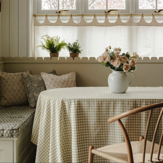 Nestled nook with a checkered tablecloth, floral arrangement, and cushioned bench.
