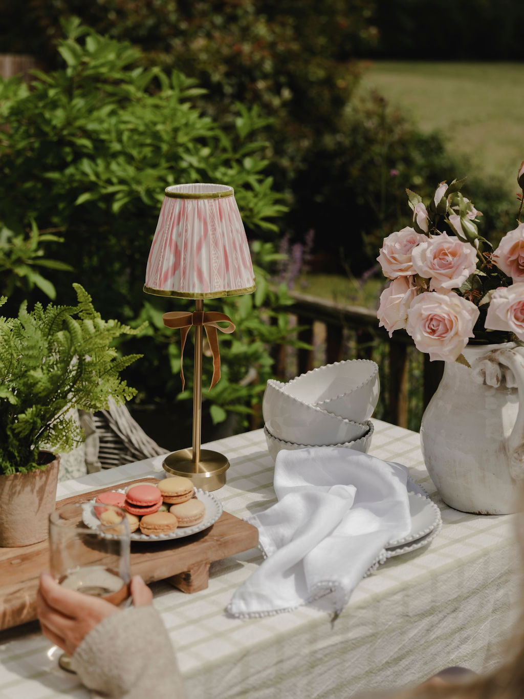 Outdoor setting with a table featuring a lamp, macarons, and flowers.