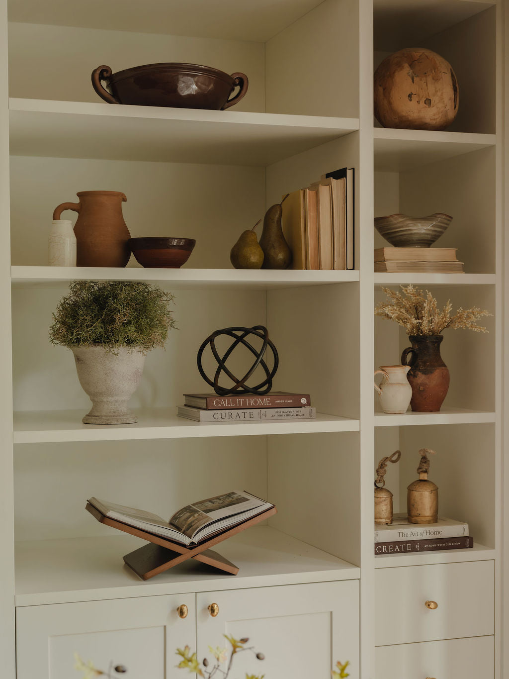 Ceramic pears styled on shelf with faux foliage and books