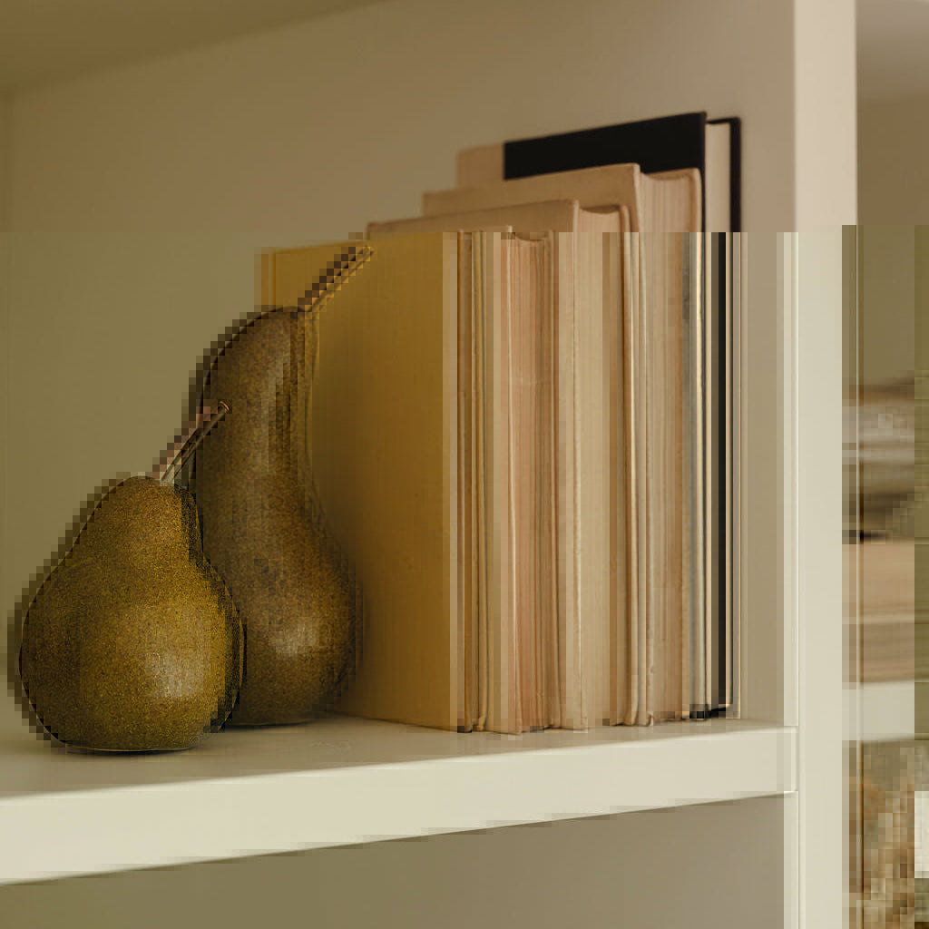 Ceramic pears styled on shelf with faux foliage and books